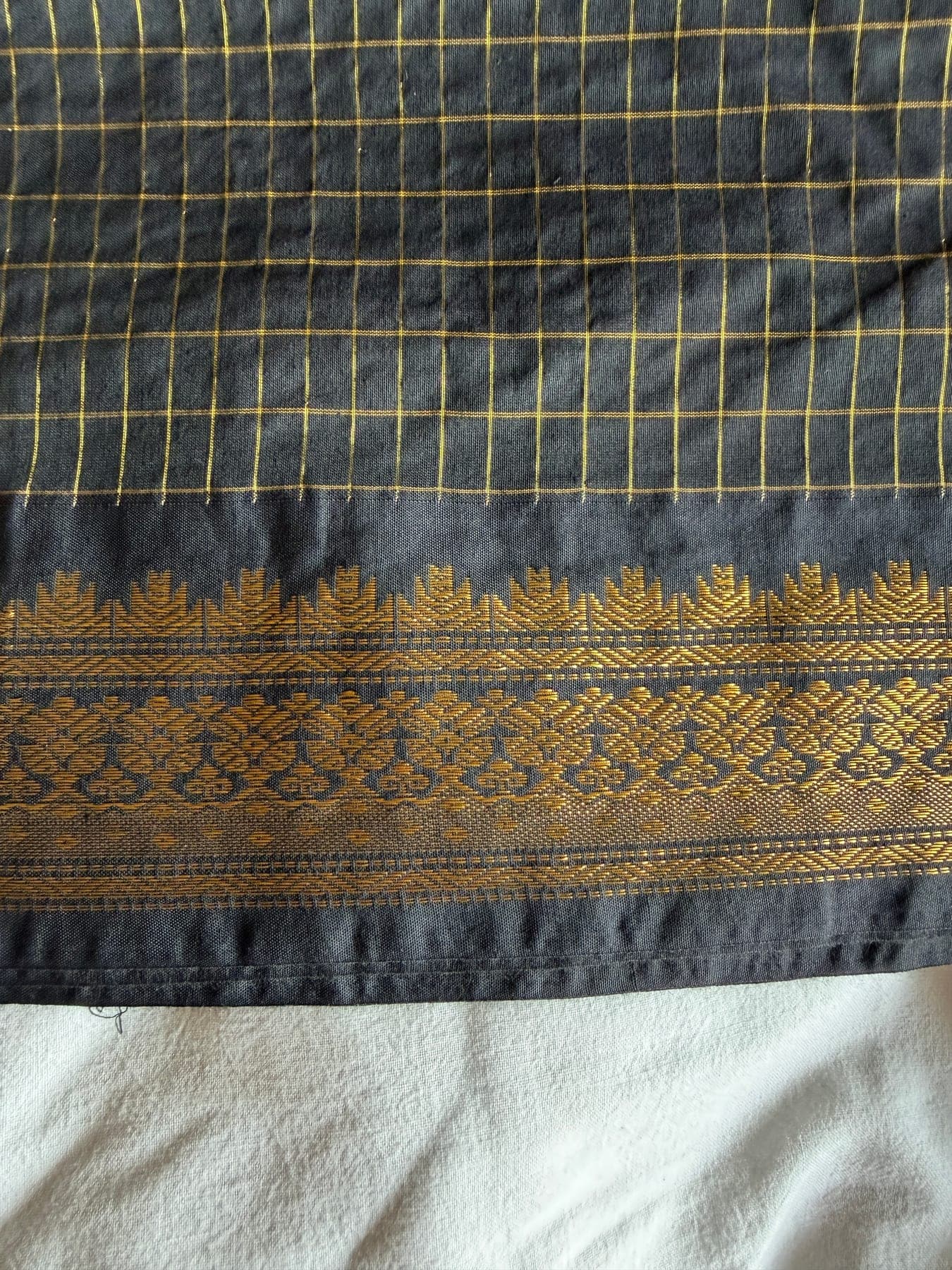 Self-shot close-up showing the saree grid pattern and woven gold border.