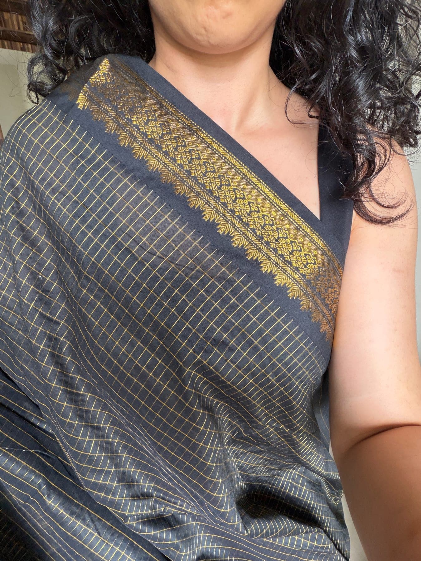 Self-shot reference showing the black and gold saree draped on a person.